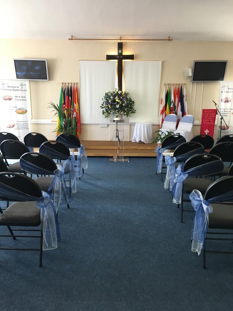 photo of the church set up for a wedding with grey chairs and blue ribbons